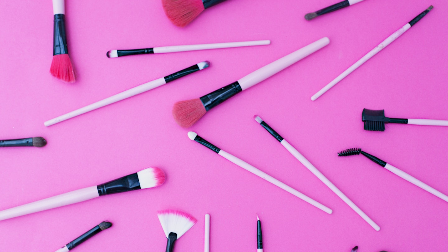Makeup brushes on a pink background