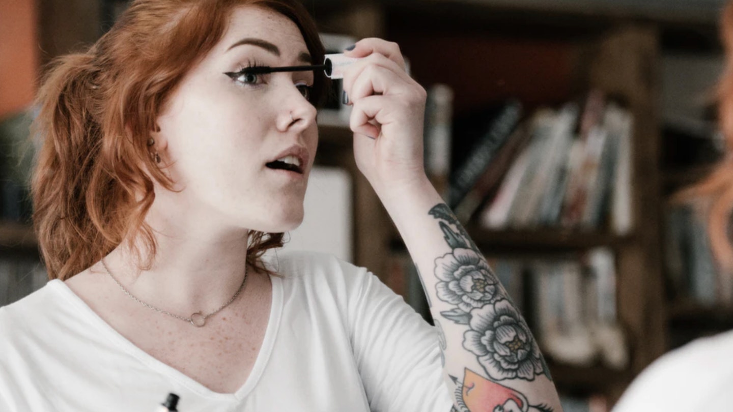Best Concealers: Woman doing makeup with tattoos on arm