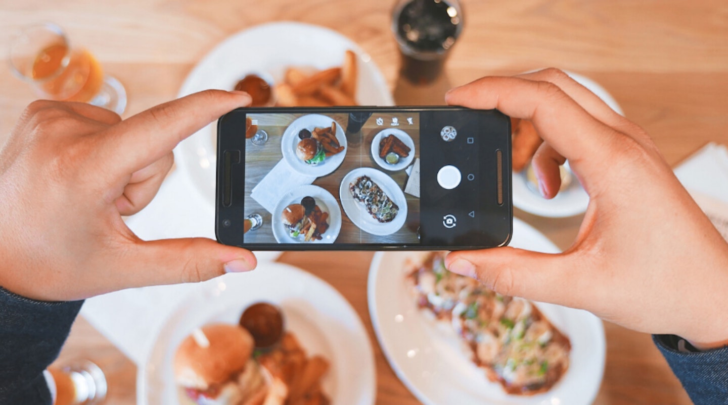 Person taking photo of food on iPhone