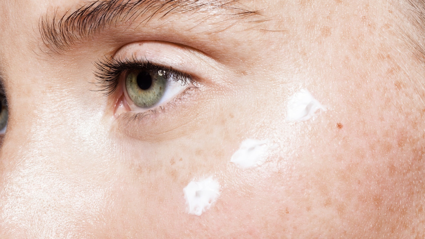 Woman's face with cream under eye