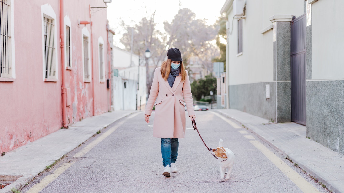 Woman walking dog in face mask