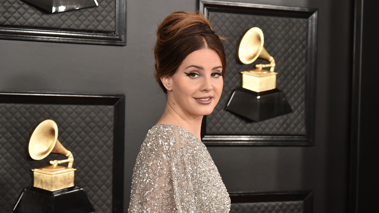 lana del rey gold dress Lana del Rey opted for a Valentino Custom gold chantilly lace waisted dress with an ankle-length flared skirt and beige satin belt, designed especially for her by Alessandro Michele for her UK