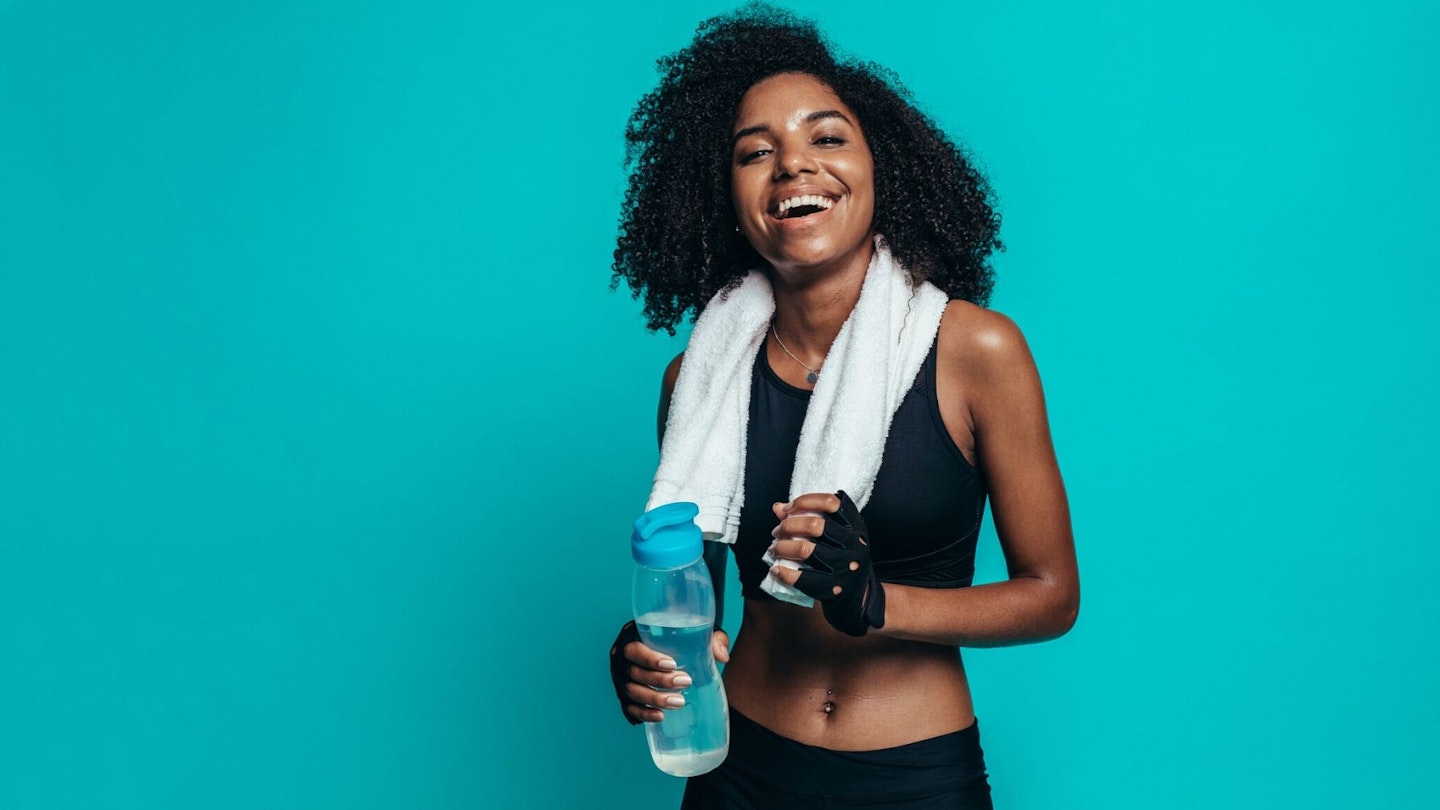Happy young woman resting after workout on blue background