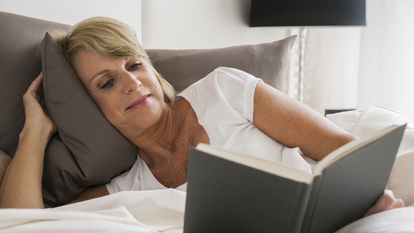 mature woman reading in bed 
