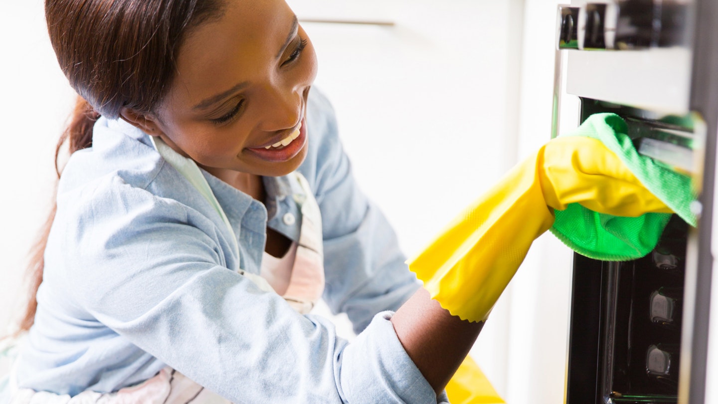 Best oven cleaner: woman cleaning oven wearing rubber gloves