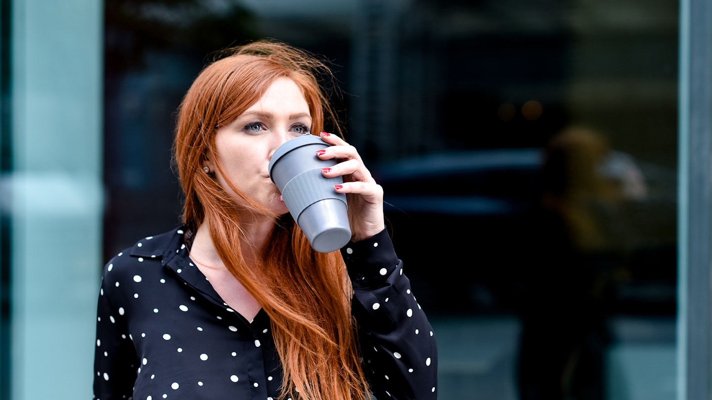 Woman drinking from a reusable coffee cup
