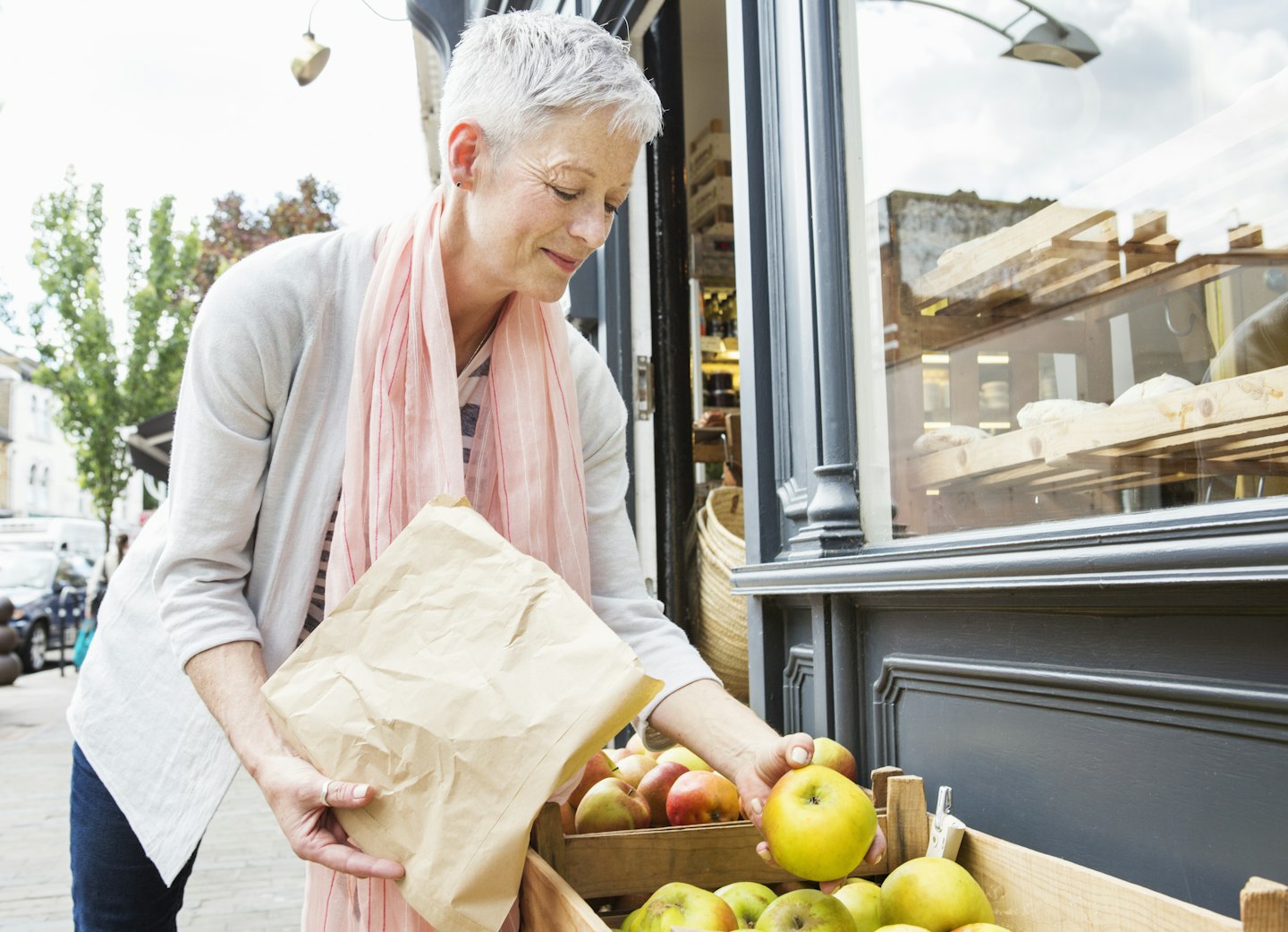 senior woman selecting organic apples from tray