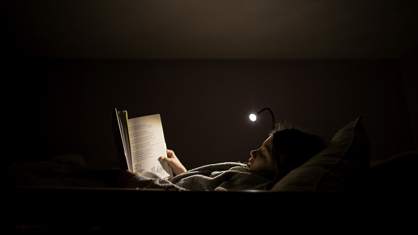 Young person reading with a reading light 