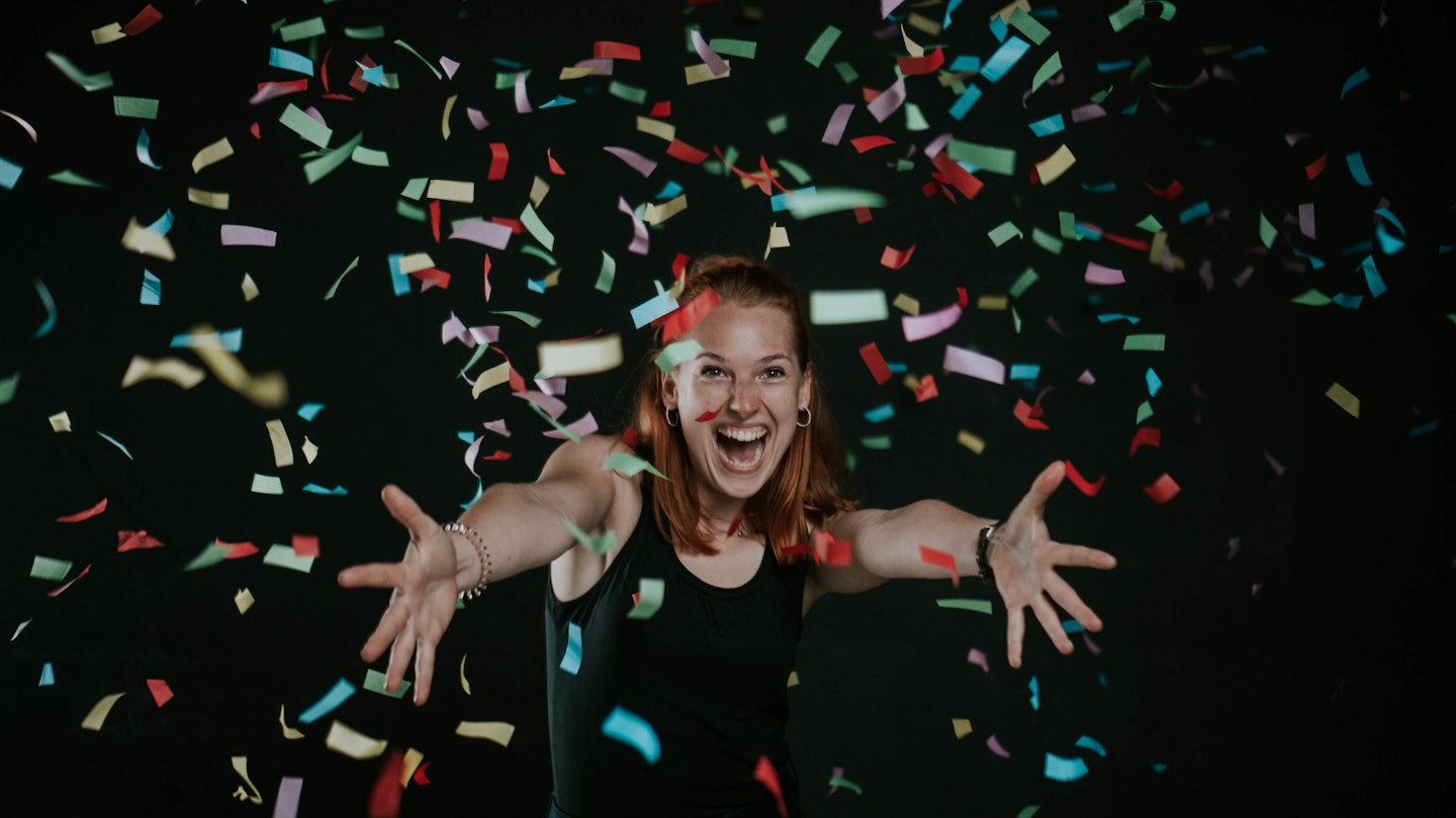 Birthday girl dancing in confetti with a black backdrop