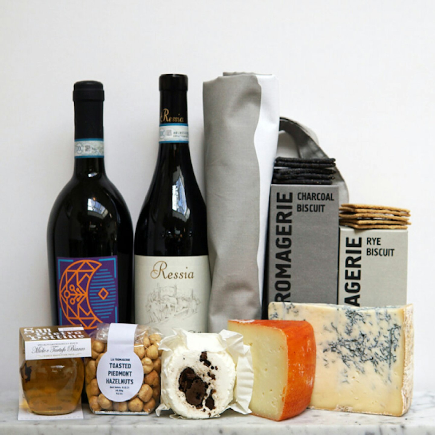 Box with three cheeses, two bottles of wine and crackers