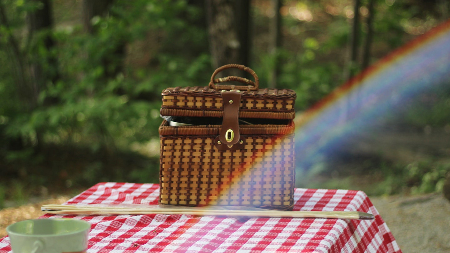 Picnic basket on an outside table with a checked table cloth