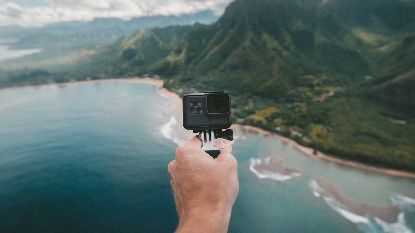 Black Go Pro in action on selfie mode sticking outside of a helicopter over the sea