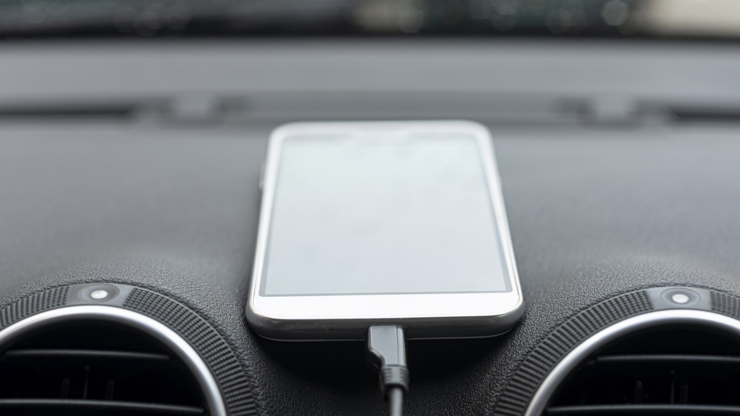 A mobile phone on a car's dashboard 
