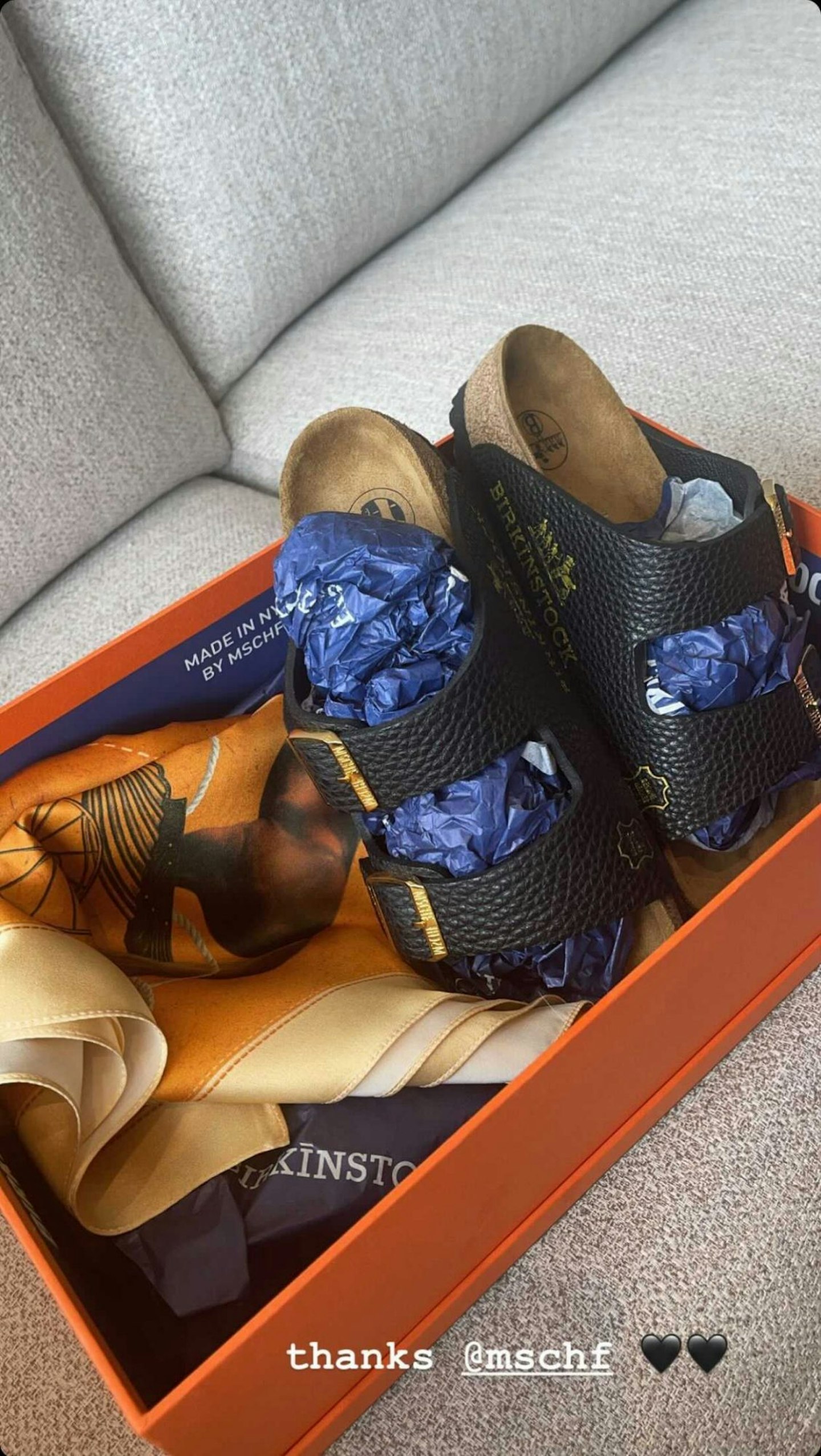 A box containing a pair of black sandals 