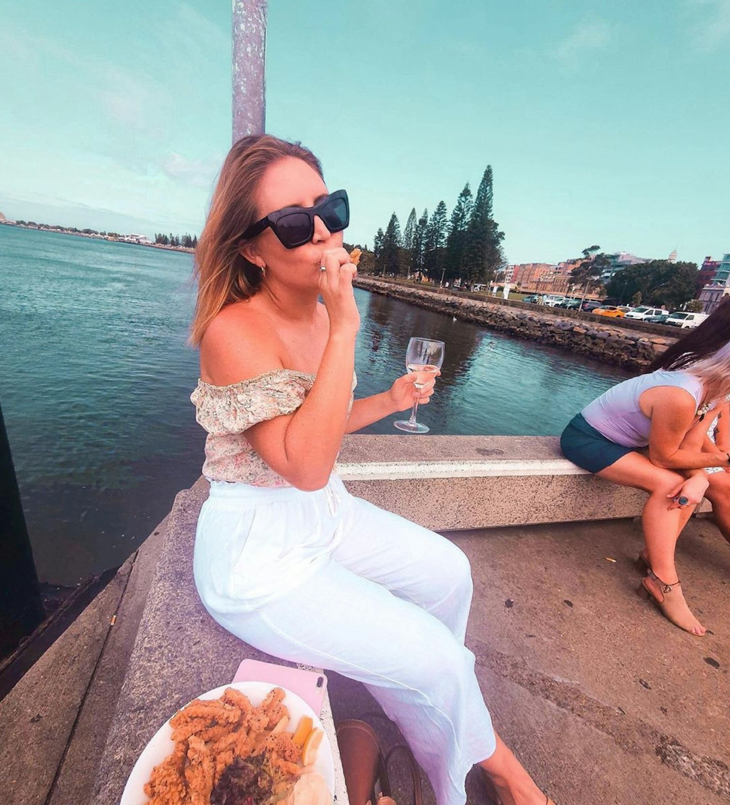 Lauren Huntriss poses by water with shrimp in hand, for her instagram