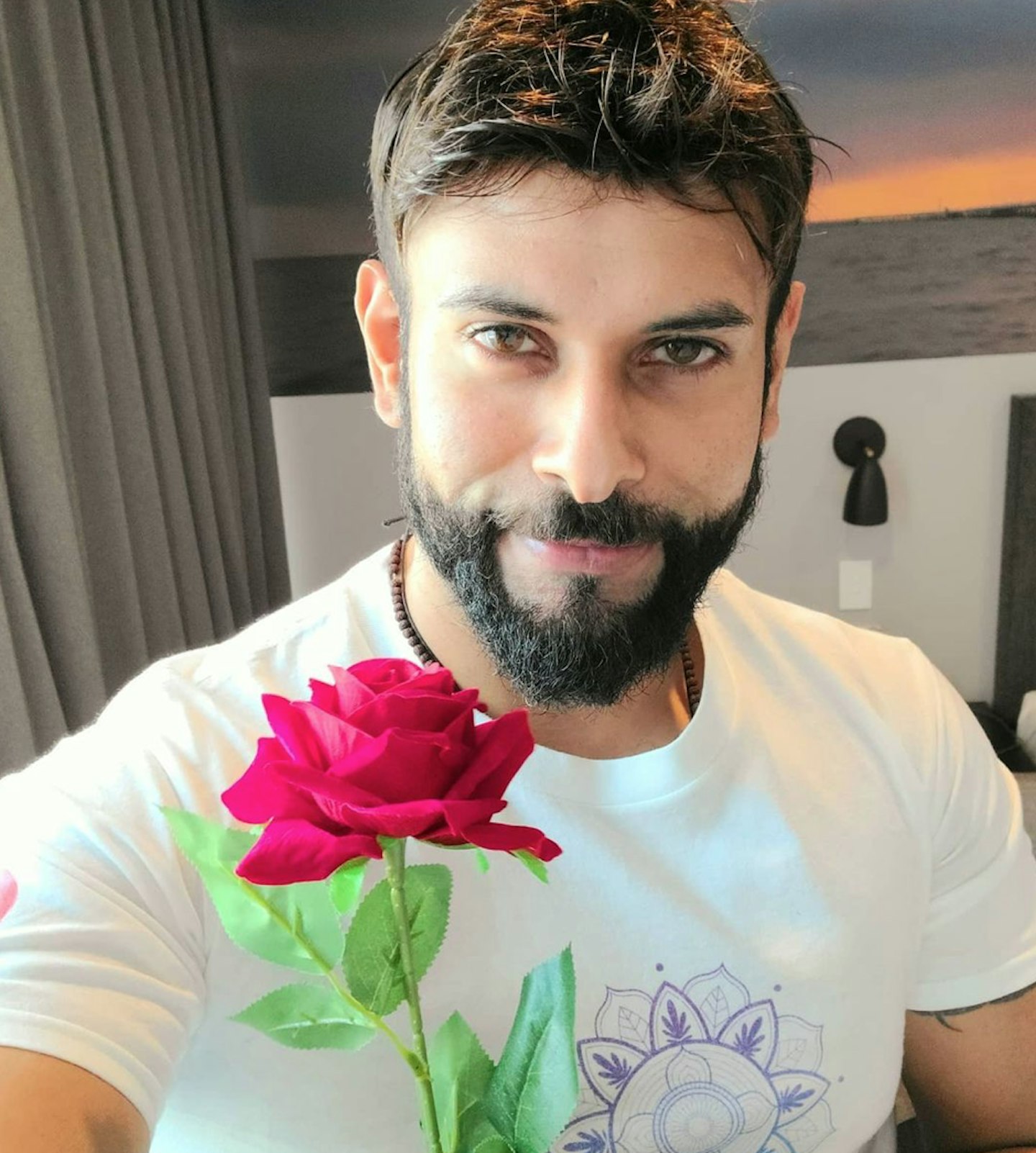 Dino Hira uploads post to instagram holding rose in hand
