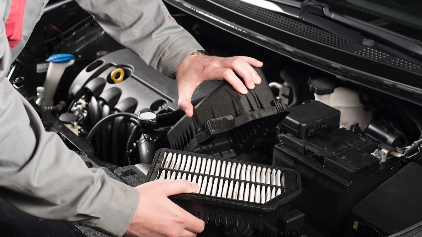 A mechanic changes a car's air filter