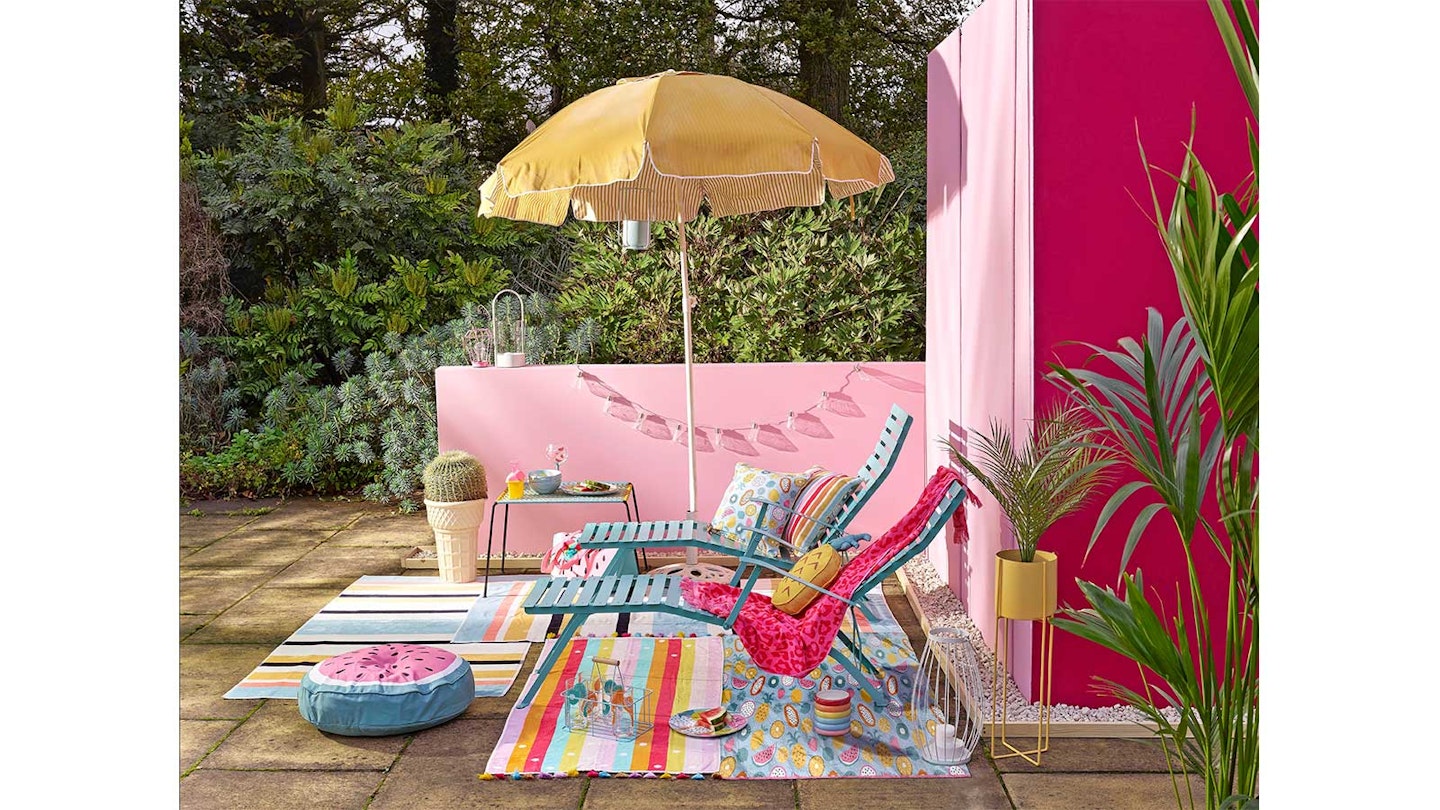 Yellow parasol and blue sun loungers in sunny garden