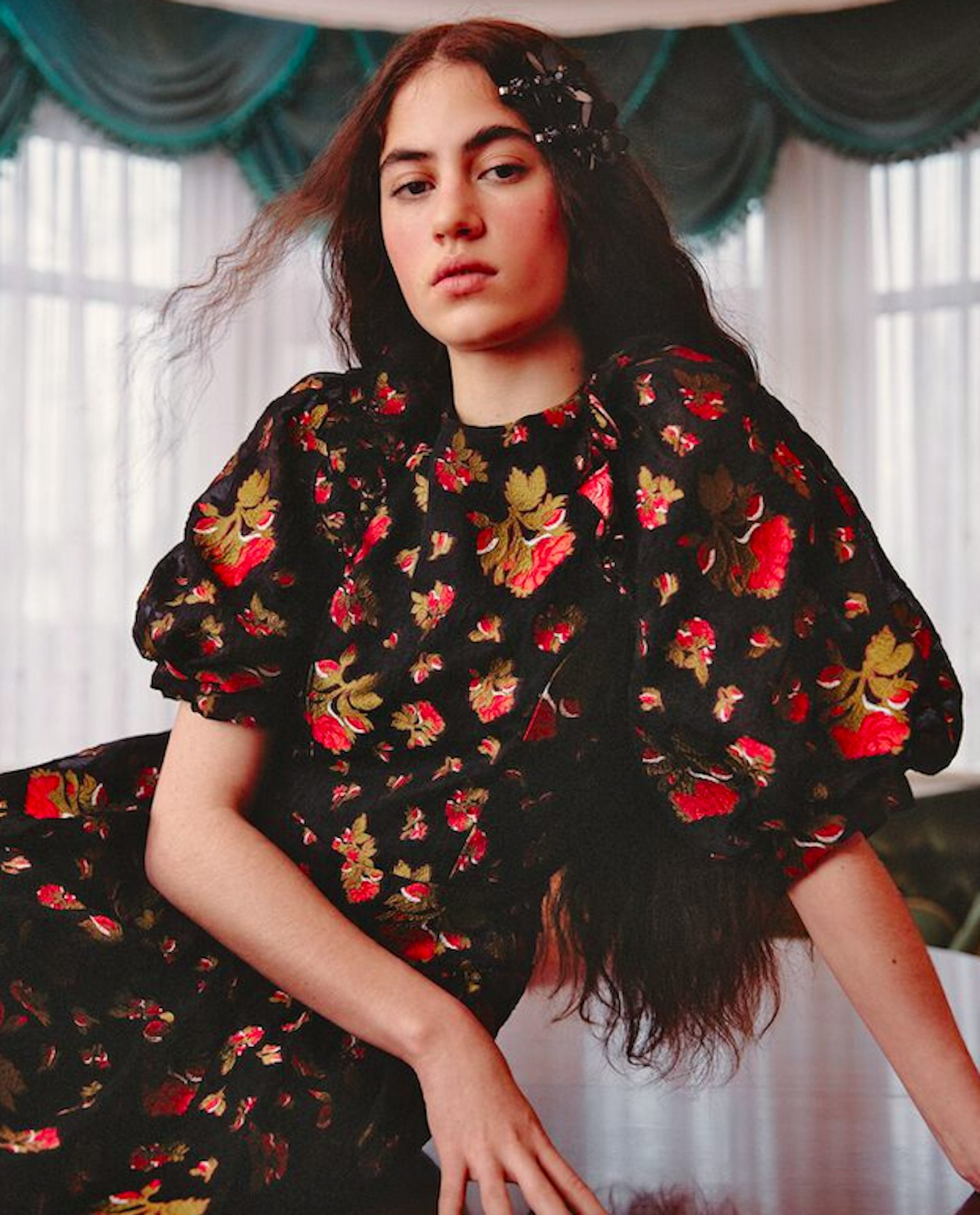 Model wearing a black dress with red flowers by Simone Rocha x H&M