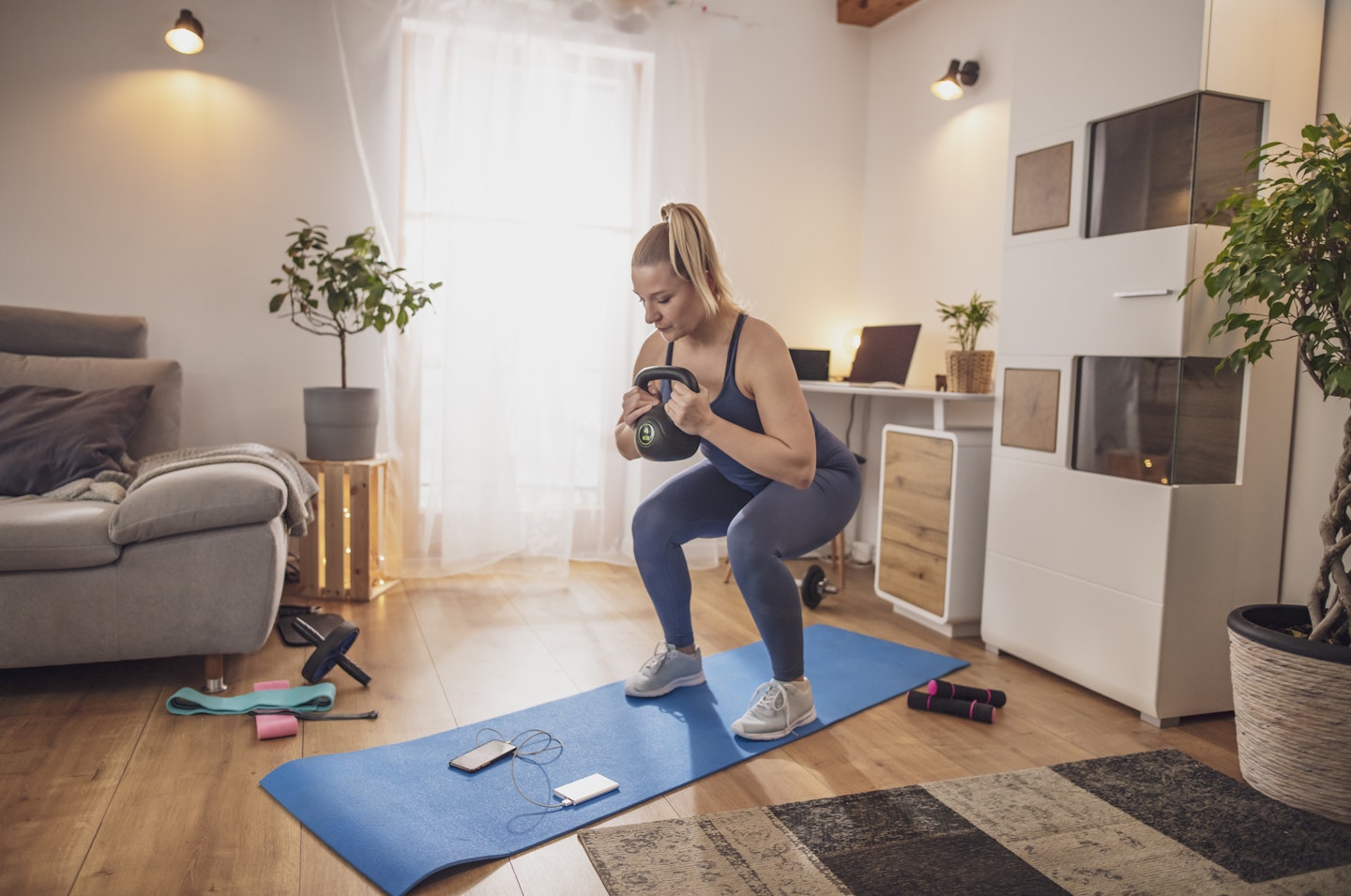 Woman squatting with kettlebell at home