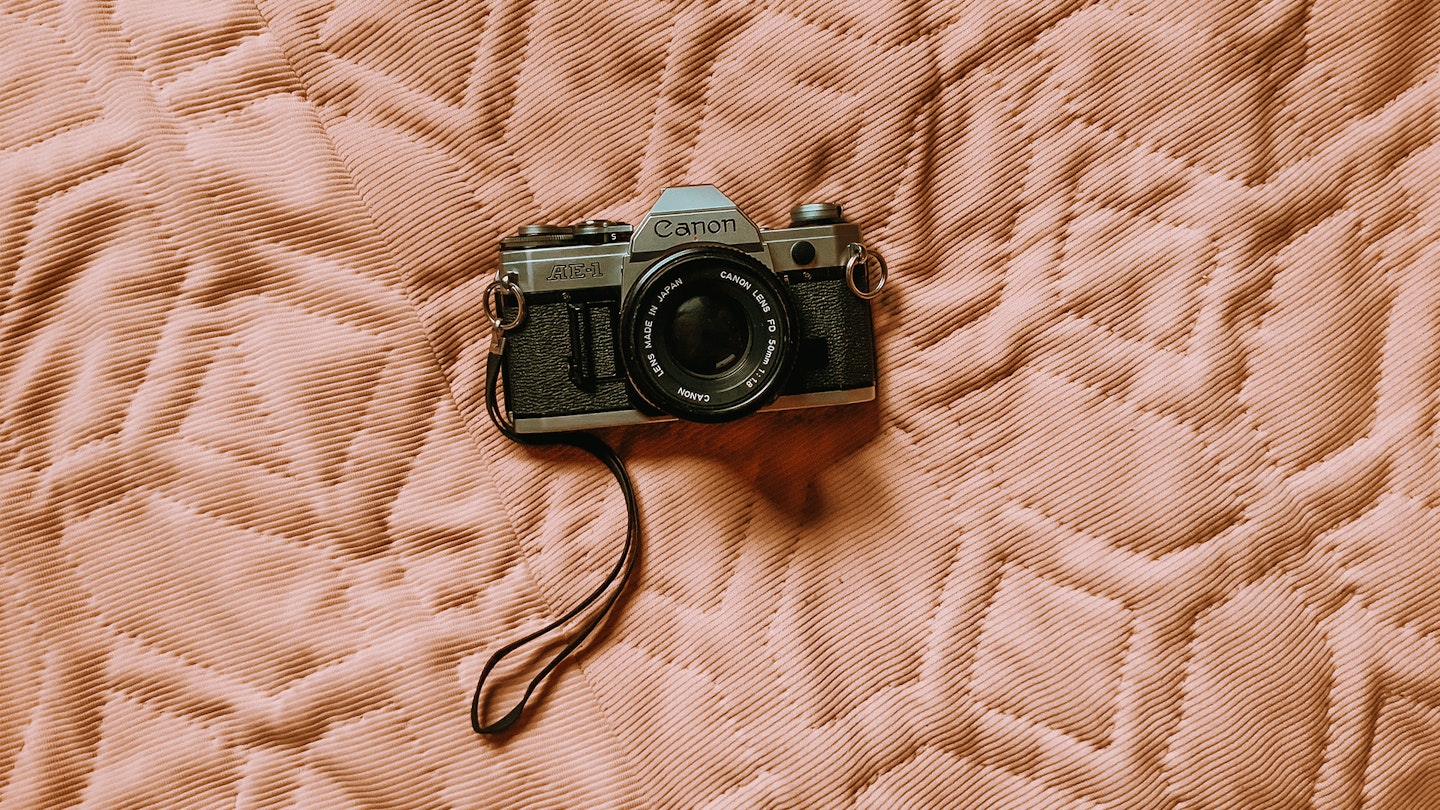35mm film camera resting on a quilted bed cover 