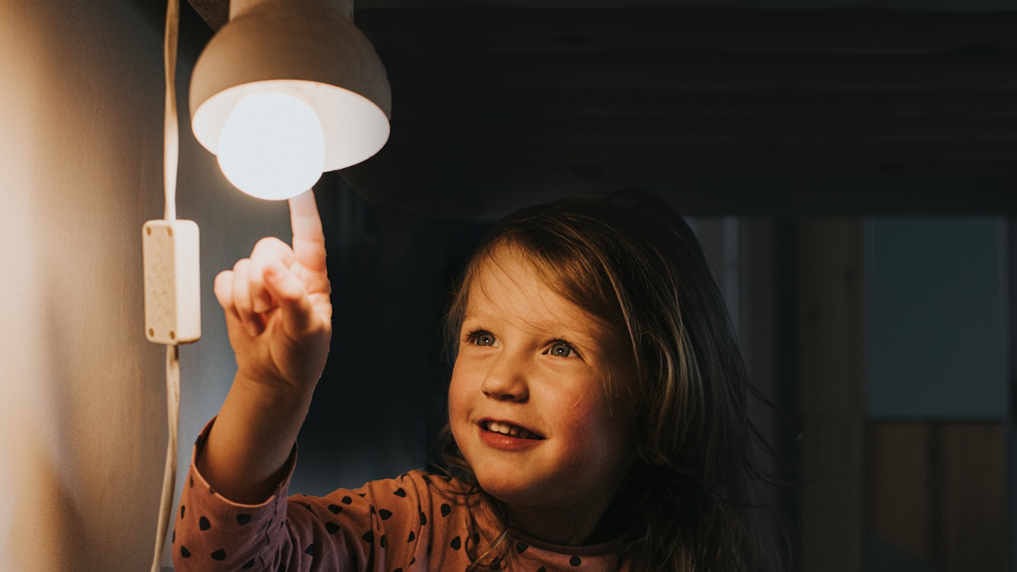 Girl poking an energy-saving lightbulb