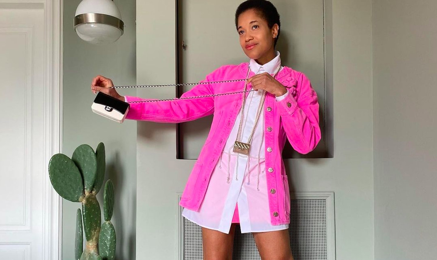 Tamu McPherson wearing a bright pink blazer and carrying Chanel bags