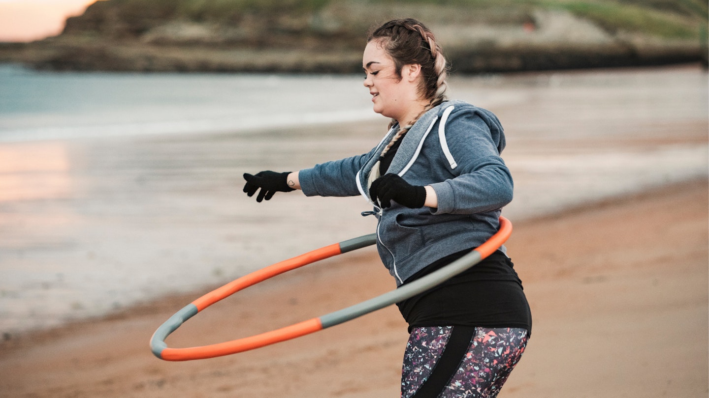 Woman on a beach using one of the best weighted hula hoop