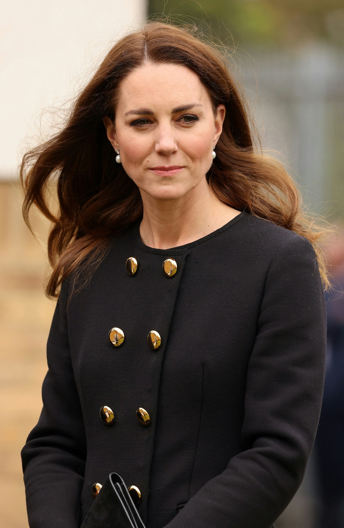 A close-up of Kate Middleton, wearing a gold-buttoned coat from D&G 