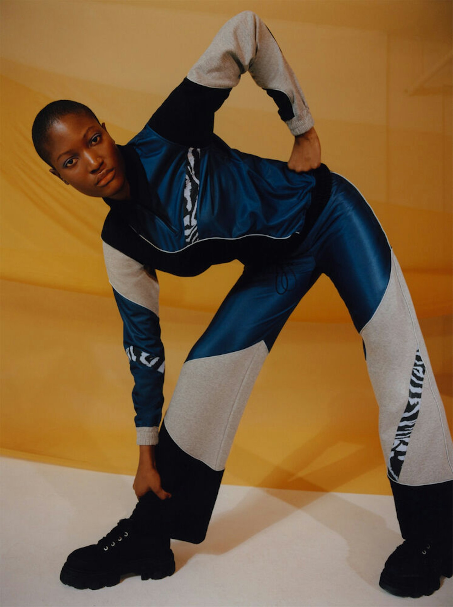 A model wearing a patchwork track top and track pants from Ganni x Ahluwalia