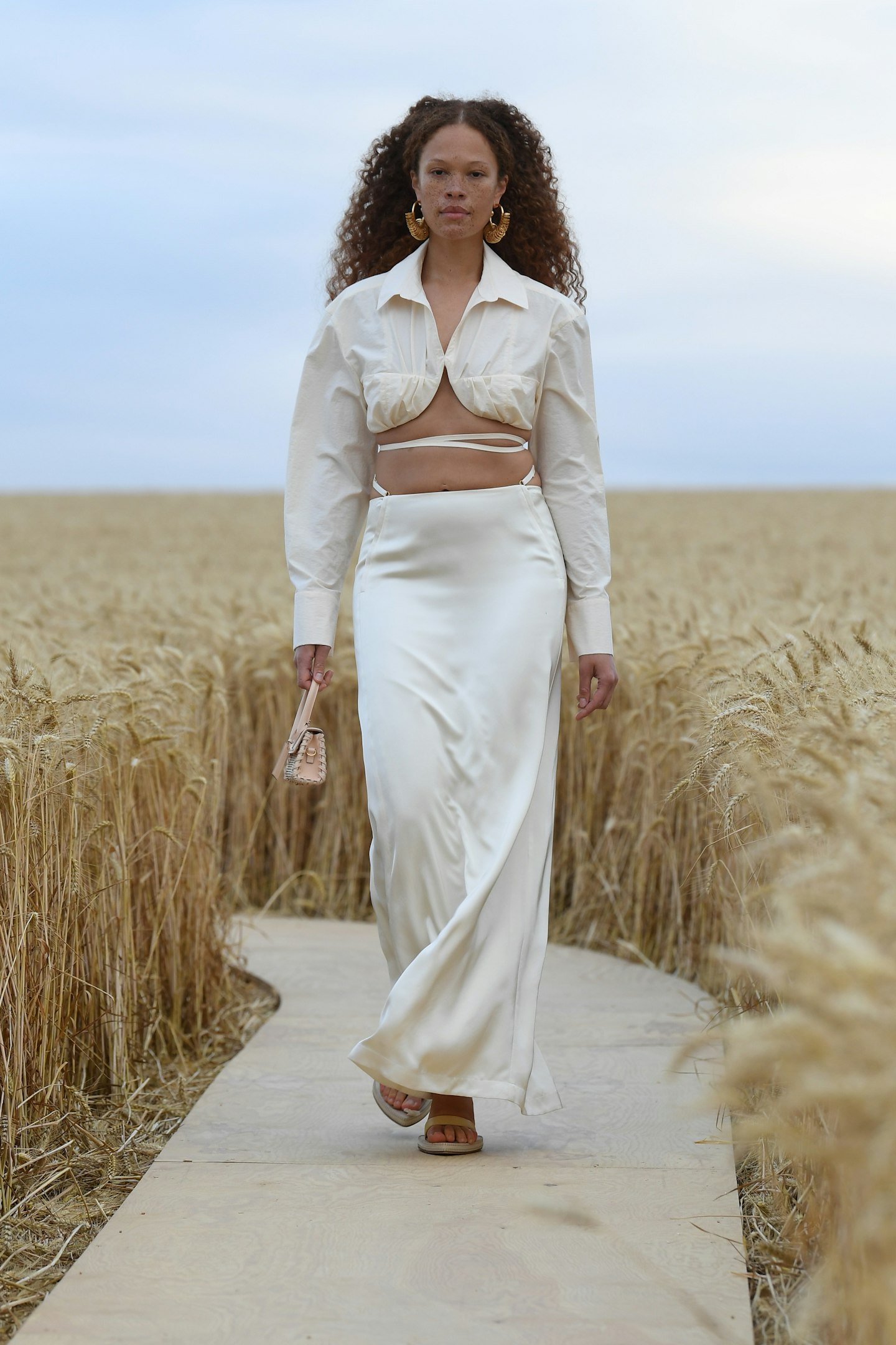 A model wearing a cropped blouse and silky skirt at Jacquemus SS21