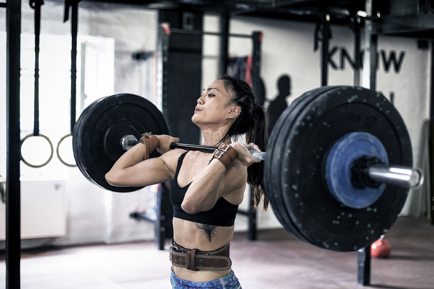 Woman lifting heavy barbell wearing weightlifting belt