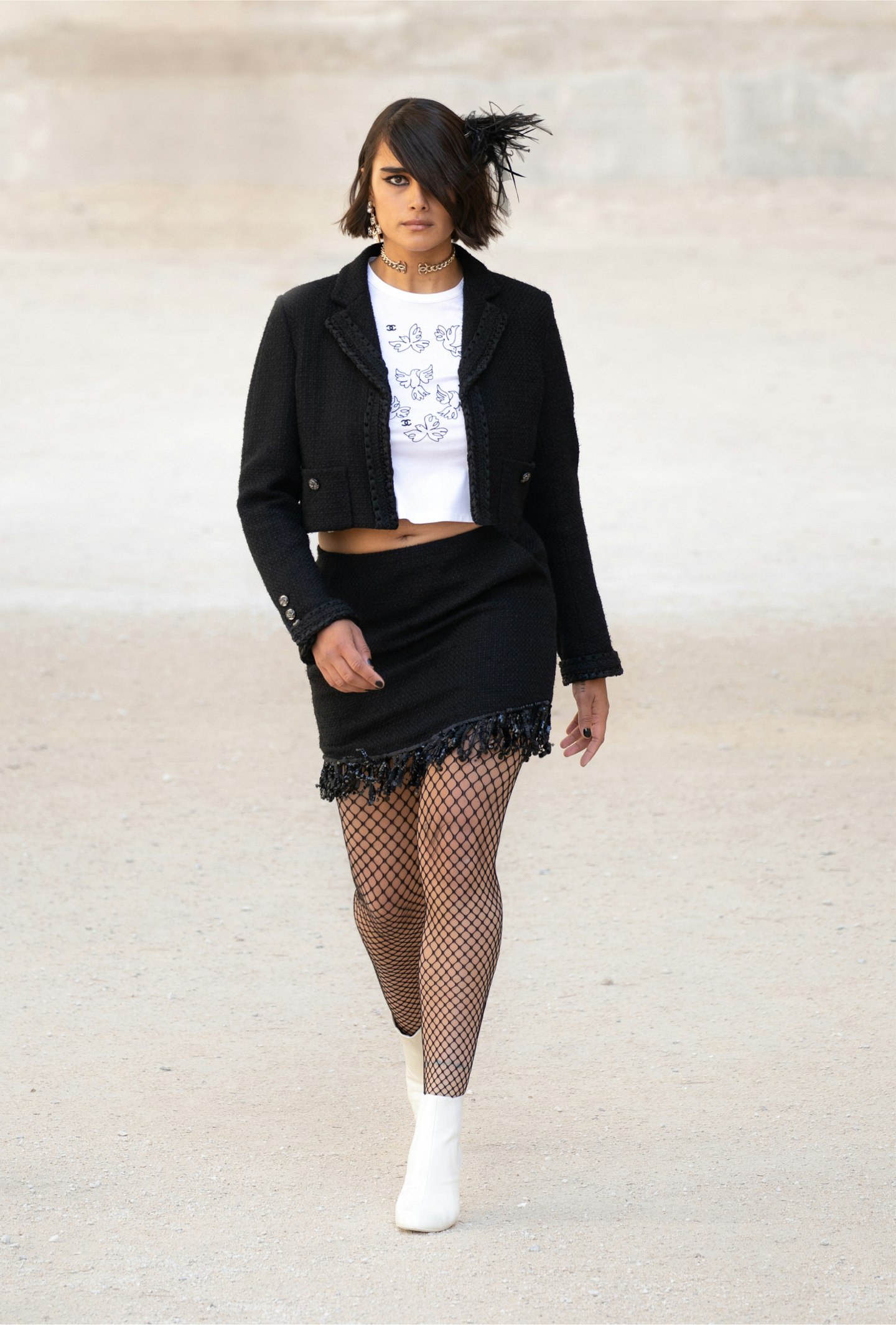 A model wearing a mini skirt and feathered hair pin at Chanel Cruise 2021/22