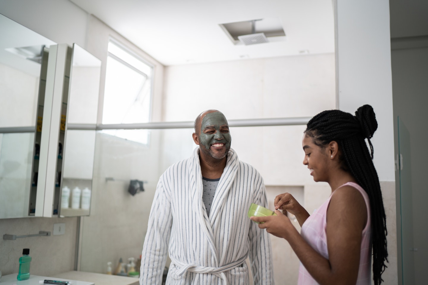 Man applying face mask with daughter