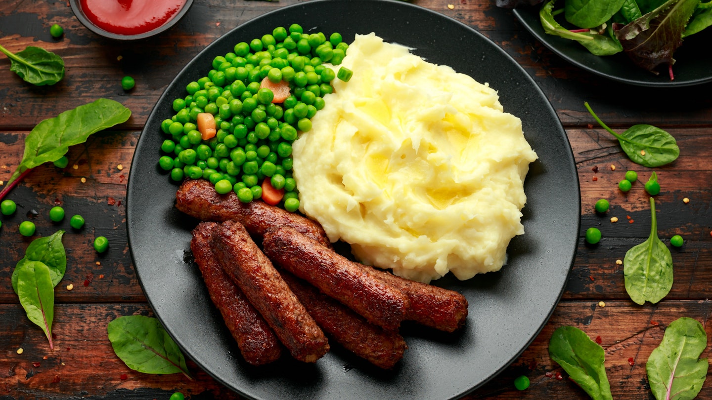 Some of the best vegetarian sausages on a plate with mashed potatoes and peas