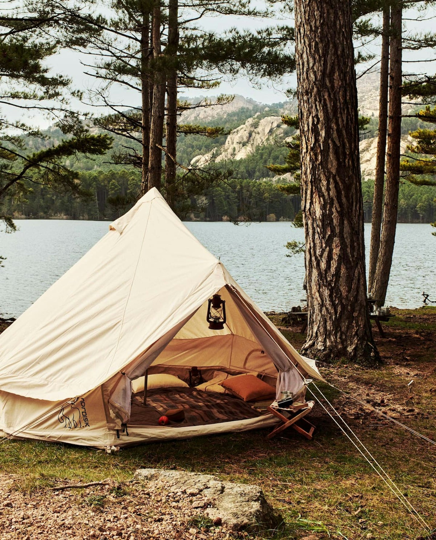A tent from Nordisk pitched in a forest by a lake 