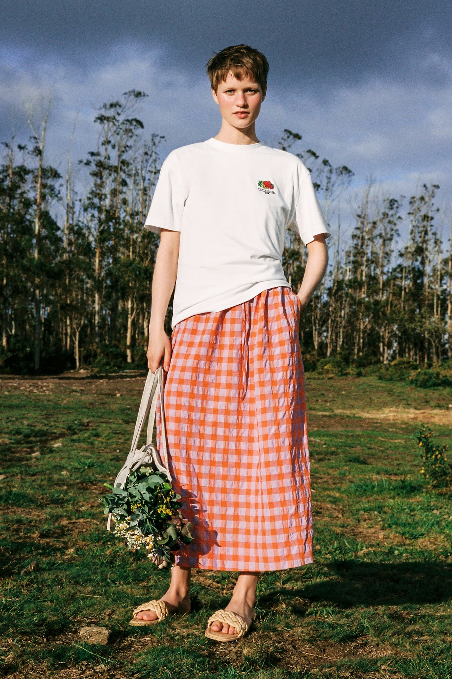 A model wearing a checked skirt and carrying a flower bag