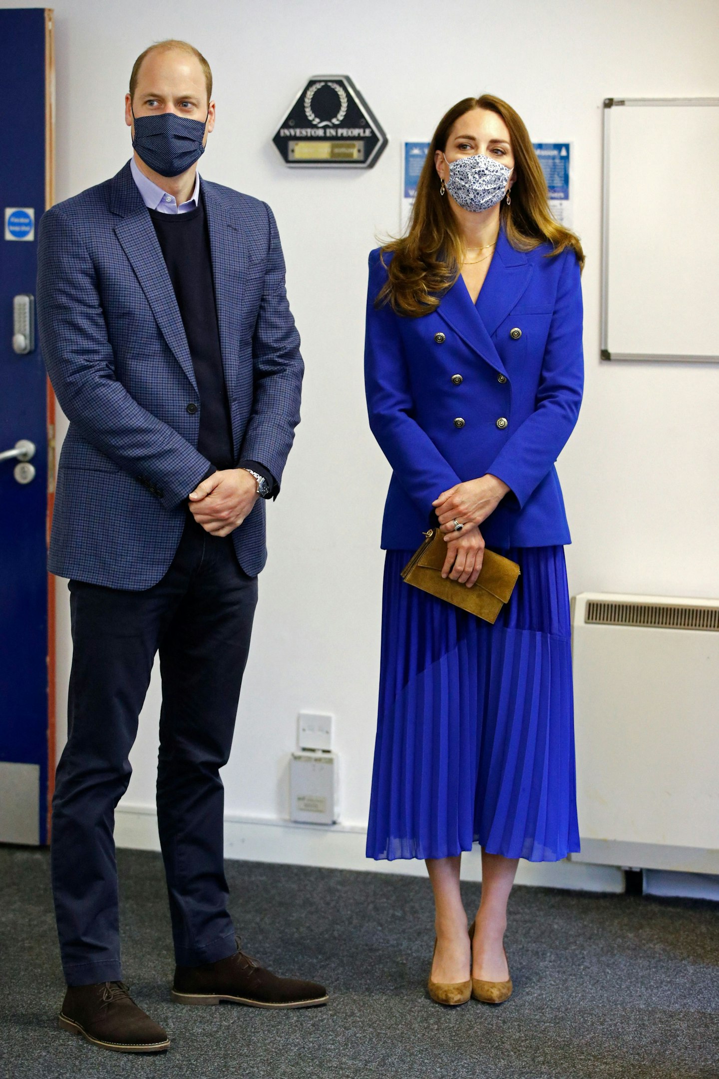 Kate Middleton wearing a bright blue suit jacket and pleated skirt 