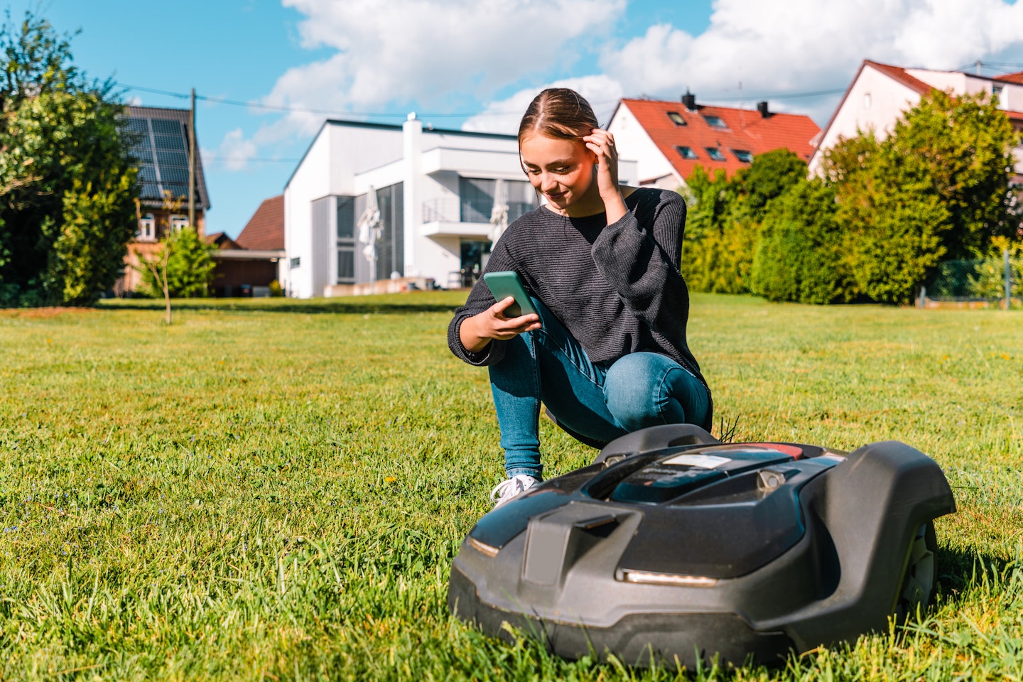 A girl using a smartphone to set up a robot lawnmower