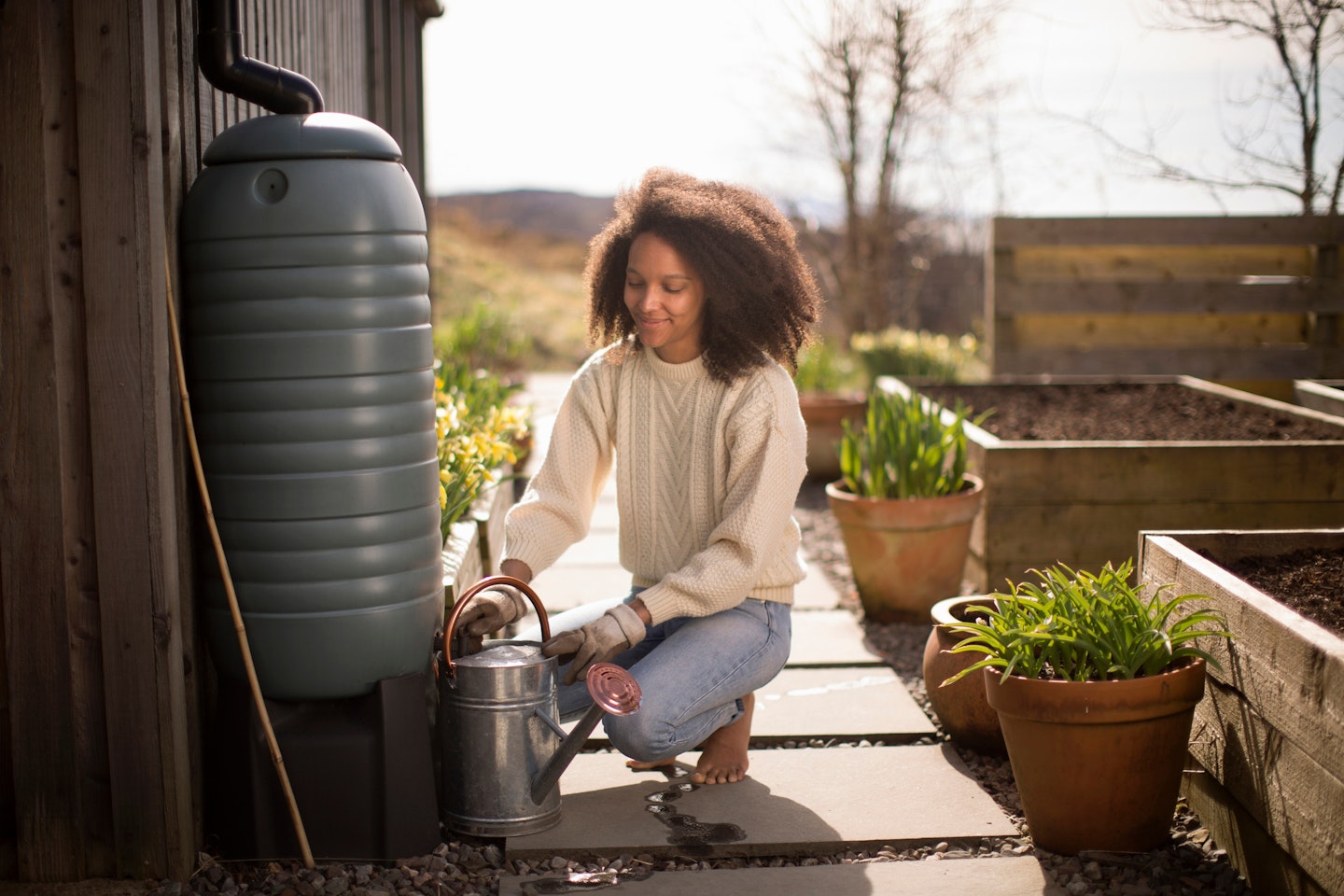 women filling watering can with water butt - rainwater catcher