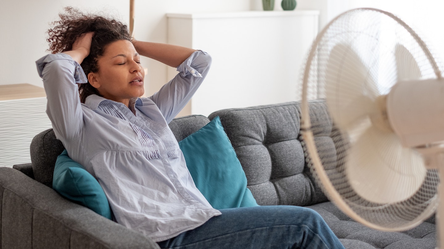 woman cooling down in front of fan on sofa