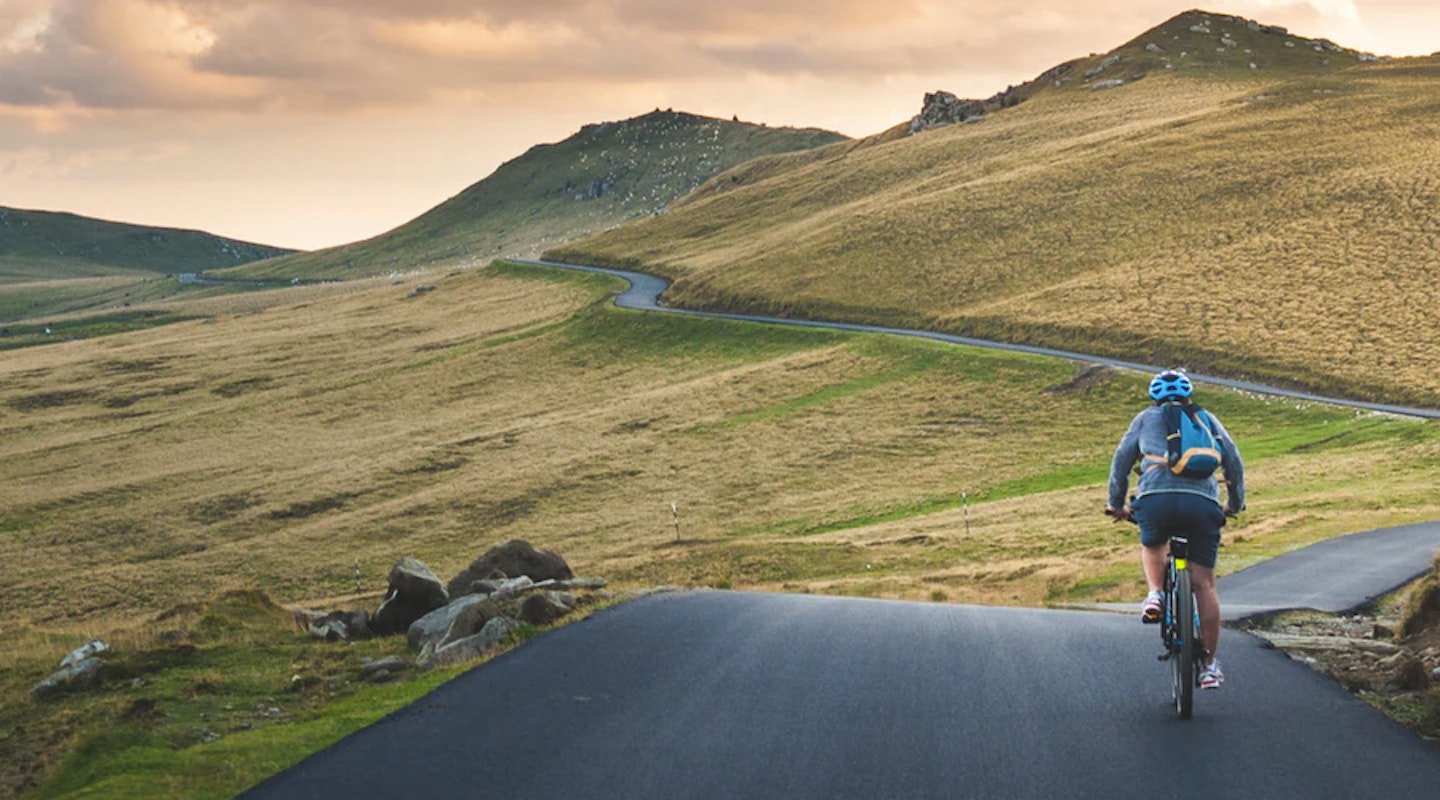 Person riding bike on road with hills