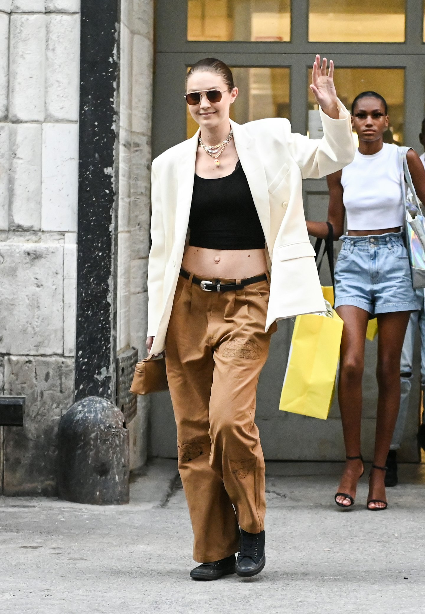 Gigi Hadid wearing a white blazer and brown trousers