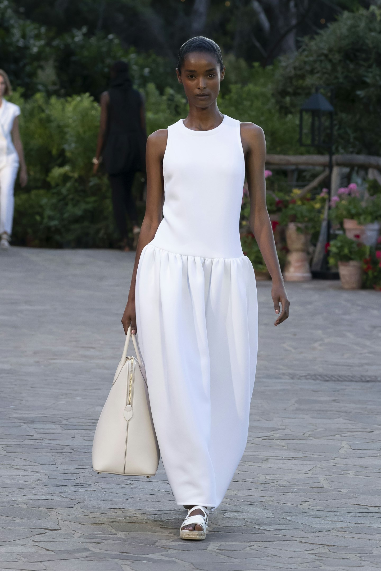 A model wearing a sleeveless white dress at Max Mara Resort 2022