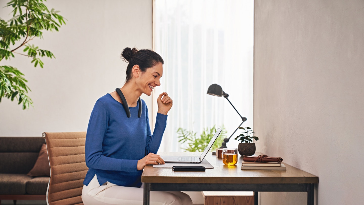 A woman, working from home with the neckband speakers