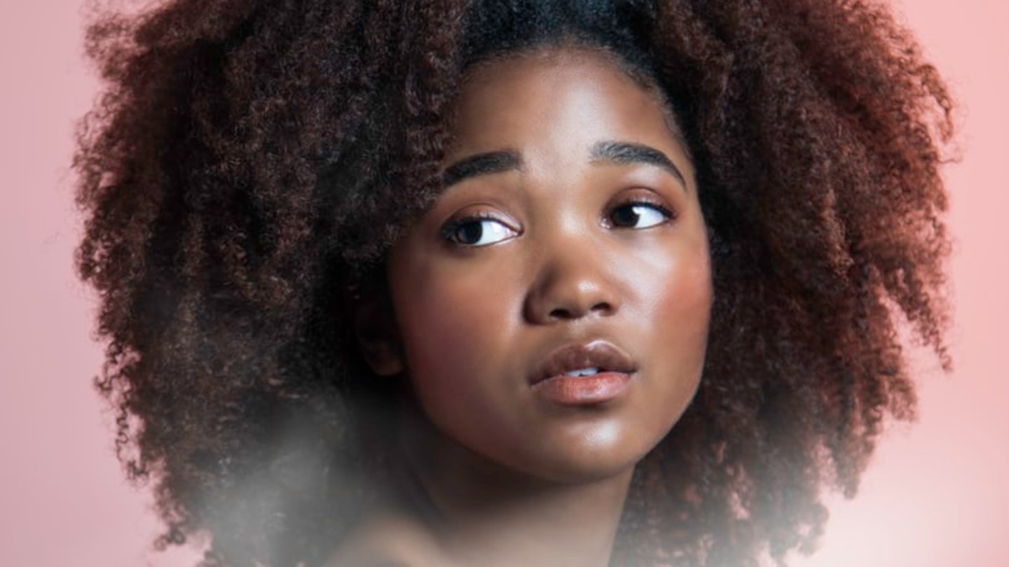 Girl with curly afro hair on pink background