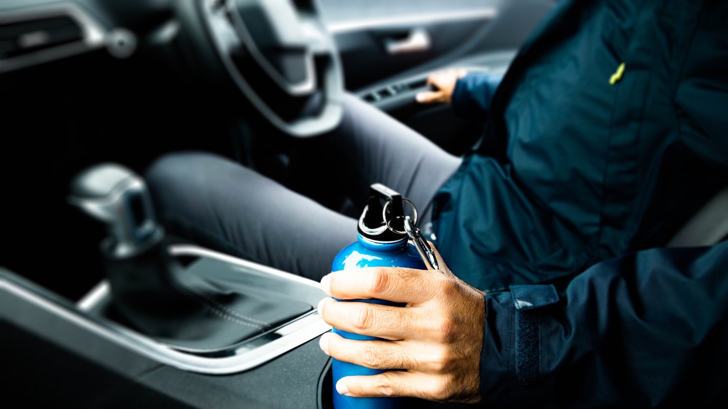 A blue flask sits in a car's cupholder