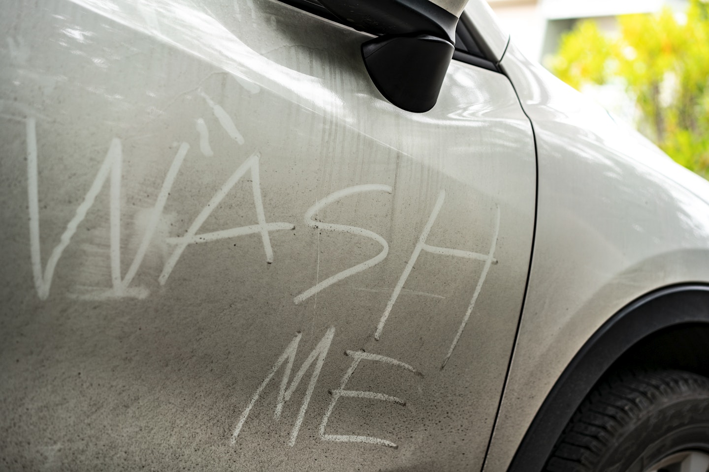 A dirty car with 'wash me' inscribed into the dirt