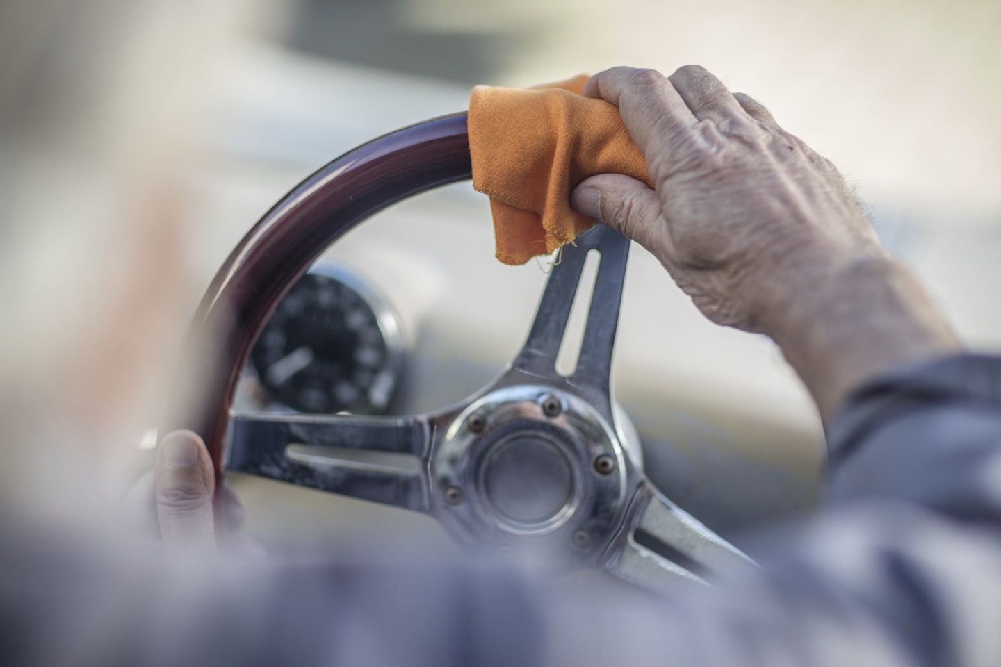 A man wiping a wooden steering wheel with a drying cloth
