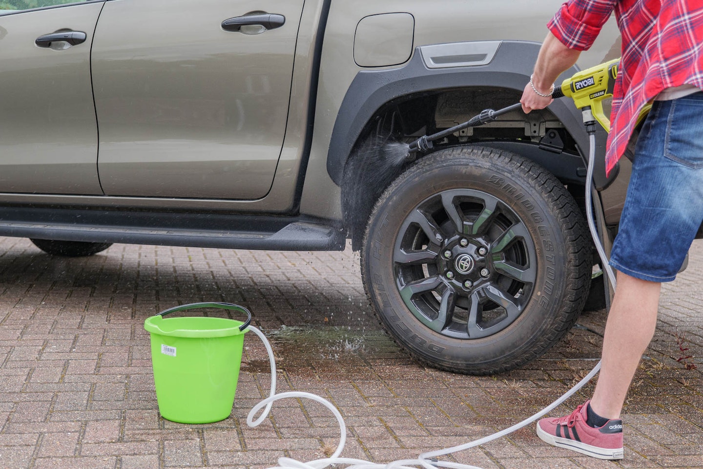 The Ryobi power washer in action cleaning a wheel